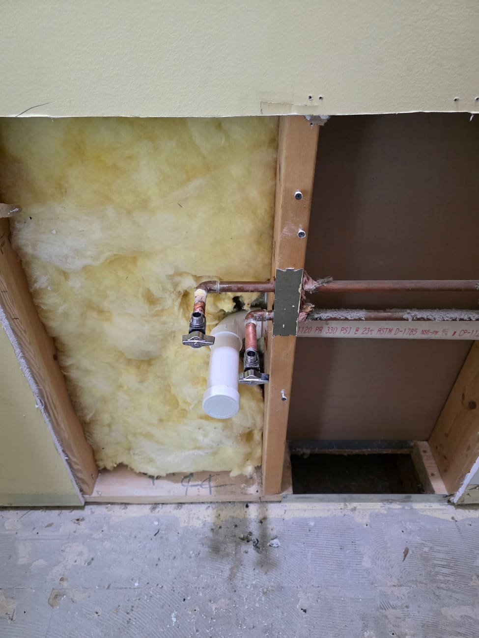 Washer box rough-in with copper hot and cold supply lines, quarter-turn shutoff valves, and a PVC drain standpipe in an open wall cavity